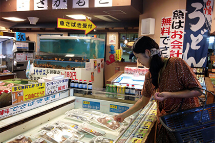 店内で魚介を眺める女性