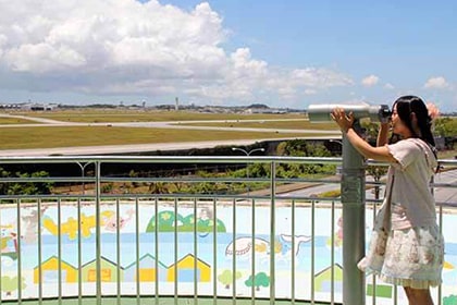 米軍嘉手納飛行場と望遠鏡をのぞく女性